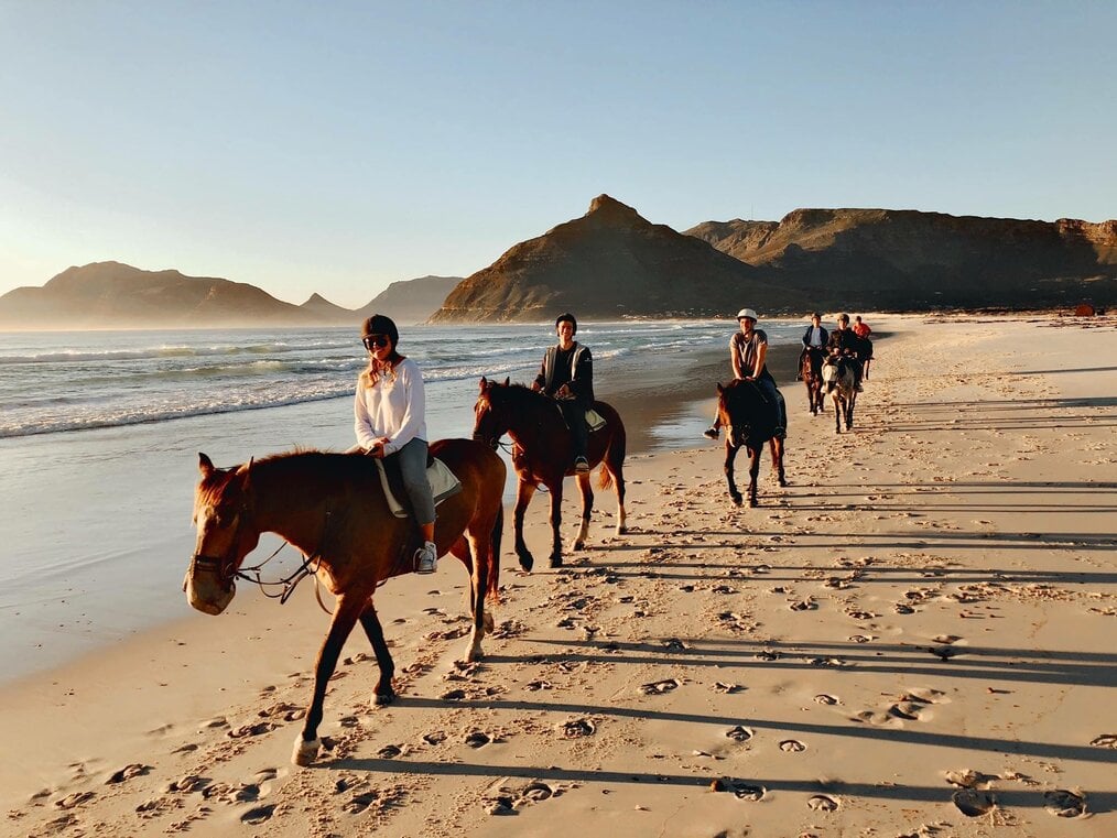 Emanuel K., iXperience Cape Town A group of people ride horses along a beach.