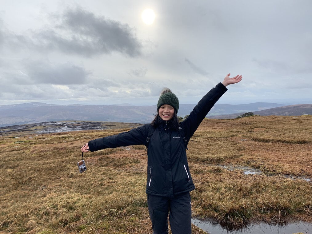 University College Dublin - Study Abroad by Carmen C A woman poses in a field with her arms in the air.